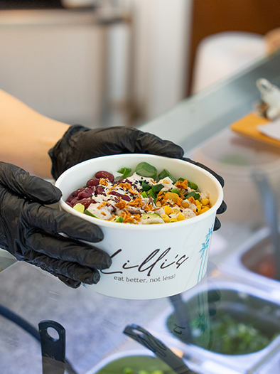 Nahaufnahme der Theke bei Lilli’s-Bowls, Bowl wird mit Handschuhen an Kunden übergeben